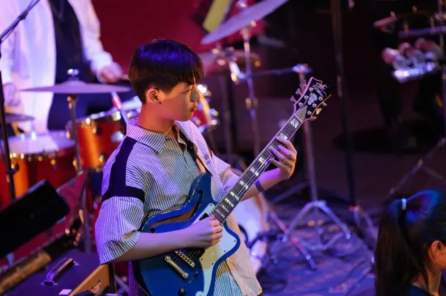 A young guitarist performing on a professionally lit stage